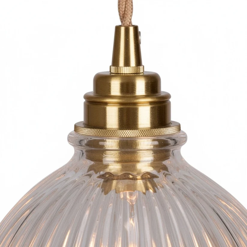 Close-up of the brass-toned fitting above the clear glass shade